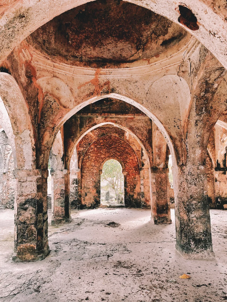 Stone columns and pointed arches recede through the Great Mosque at Kilwa Kisiwani.