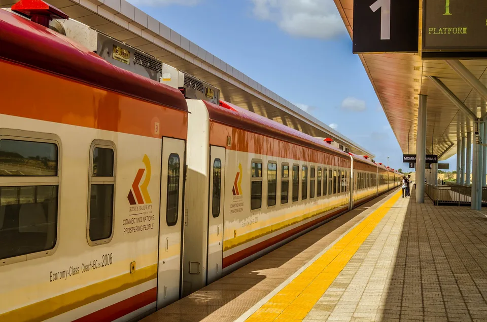 Orange-and-white Kenya Railways passenger coaches beside the platform at Mombasa Terminus.