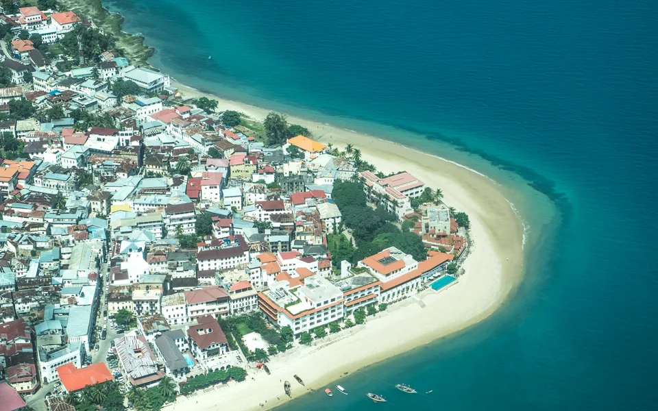 Aerial view of Stone Town’s dense buildings beside the curved waterfront, Zanzibar, Tanzania